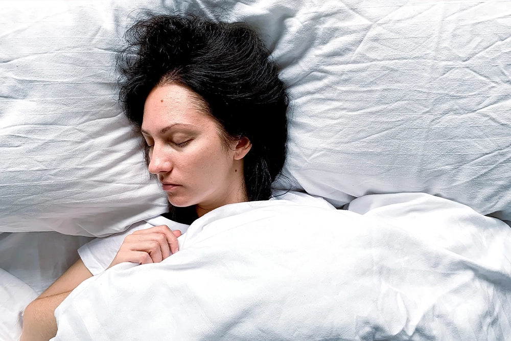 a female asleep on a white pillow with a white comforter