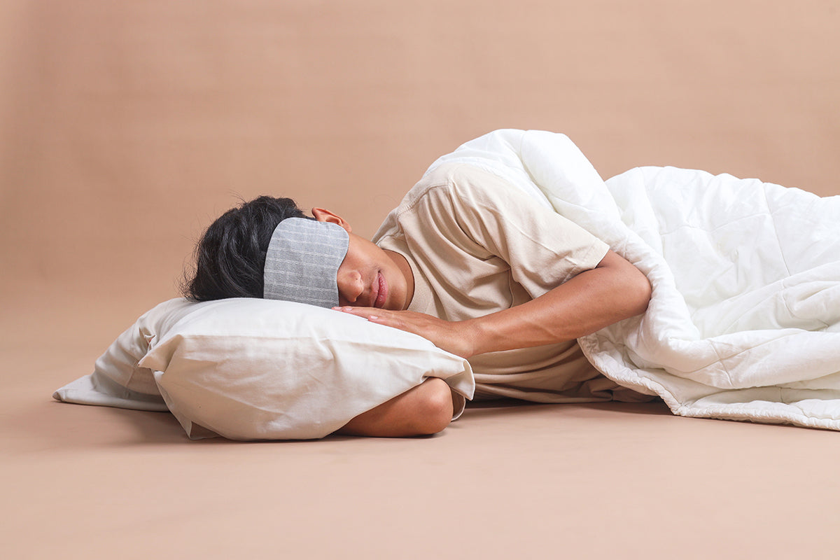 a man laying with his head on a pillow with a sleep mask over his eyes